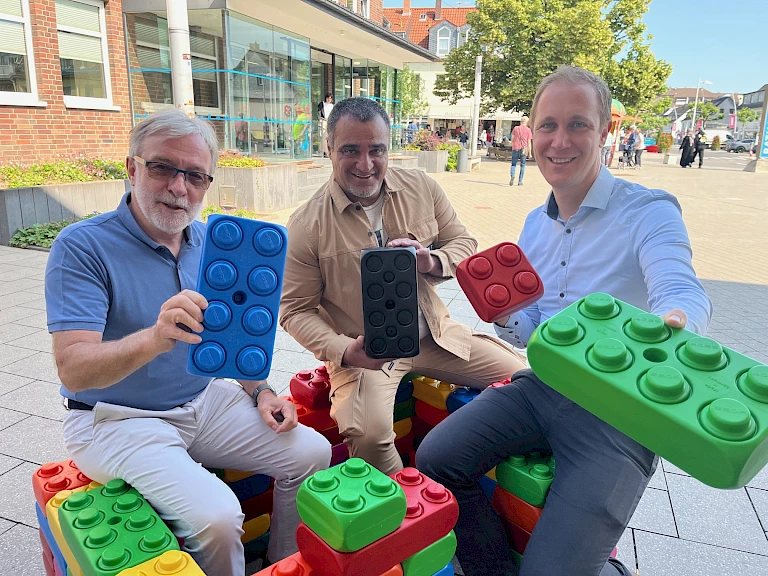 Hausbau mit Klemmbausteinen, kann das klappen? Gernot Paeschke hat so seine Zweifel, BM Daniel Zimmermann und Erhan Güneser, Gründer & Vorsitzender des Internationalen Sport- und Kulturvereins Monheim e.V., nicht. Foto: Stadt Monheim am Rhein/Tanja Bamme